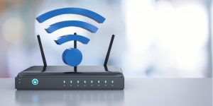Black router on a desk with a WiFi symbol on top, showcasing a central hub for wireless connectivity and network access in a workspace.