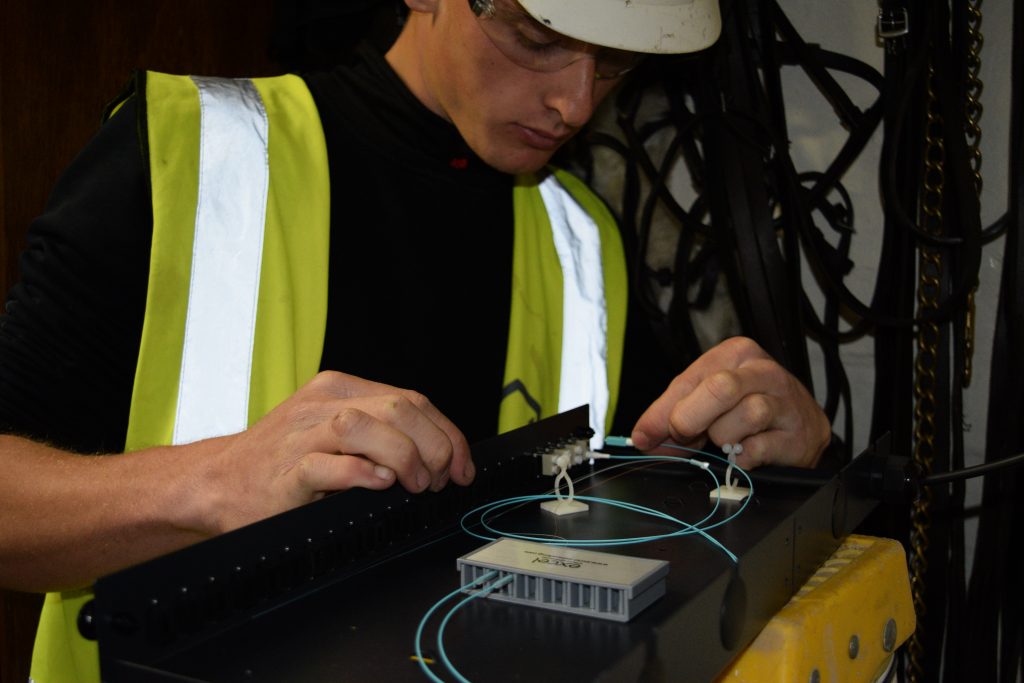 Close-up of an engineer carefully installing fibers into a fiber tray, demonstrating precision in fiber optic network setup. What is FTTP