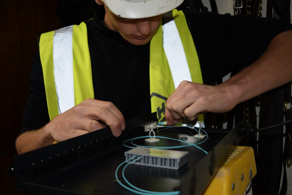 Close-up of an engineer meticulously installing fibres into a fibre tray, showcasing attention to detail in fiber optic network configuration. Fibre optic domestic repairs.