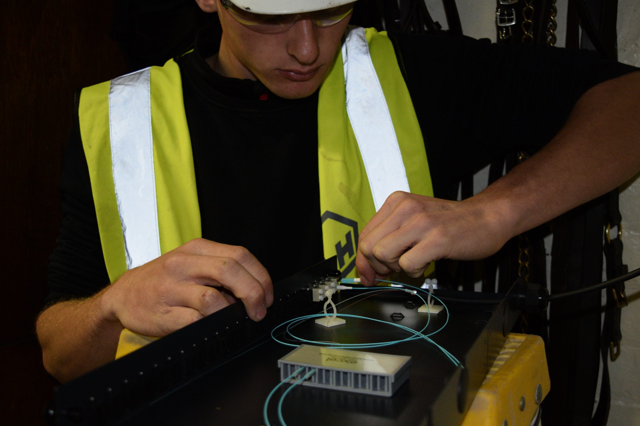 Close-up of an engineer delicately installing fibers into a fiber tray, demonstrating precision and expertise in fiber optic structured cabling network setup.
